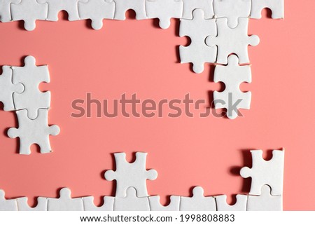 incomplete white jigsaw puzzle with plain pink background
