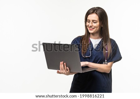 Young doctor with laptop on grey background