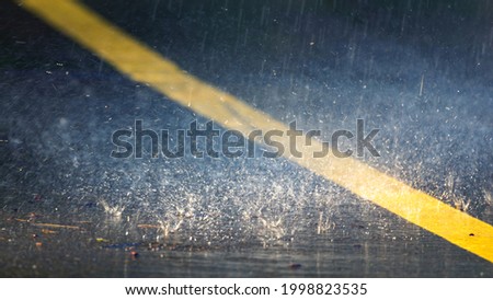 Heavy rain or downpour, raindrops fall on the asphalt, night or evening.