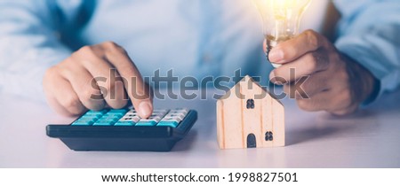 Hand of businessman planning and calculate expense and mortgage with calculator and home on desk, insurance and budget of residential, examining of loan and residence, business and property concept.