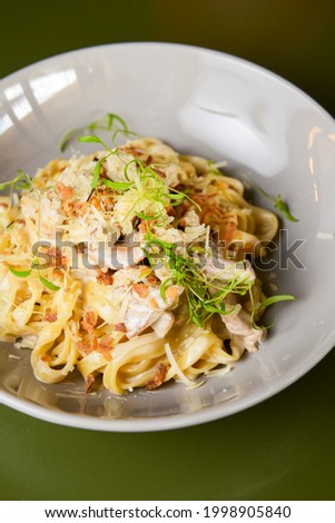 Italian tortellini pasta with cheese, sauce, and microgreens served in a white bowl. Italian cuisine concept, traditional pasta recipe.
