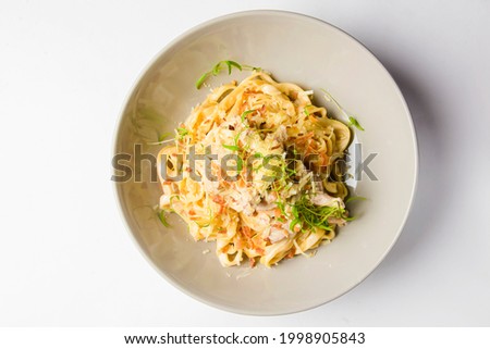 Italian tortellini pasta with cheese, sauce, and microgreens served in a white bowl. Italian cuisine concept, traditional pasta recipe.