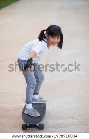 Cute little girl playing skateboard or surf skate in the skate park