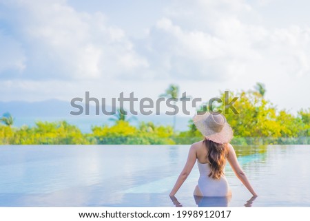 Portrait beautiful young asian woman enjoy around outdoor swimming pool with sea ocean view in travel vacation trip