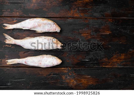 Frozen surmullet  fish set, on old dark  wooden table background, top view flat lay , with copy space for text