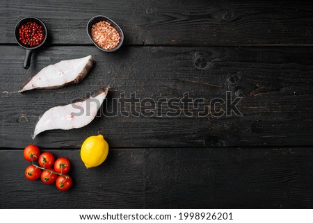 Sliced Halibut fish set, with ingredients and rosemary herbs, on black wooden table background, top view flat lay, with copy space for text