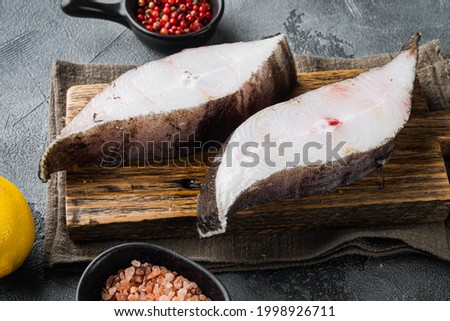 Raw halibut saltwater fish steak set, with ingredients and rosemary herbs, on gray stone table background