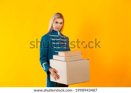 Photo of slim blonde in old-fashioned military outfit on matte yellow background. Blonde hair girl holding set of mockup boxes.