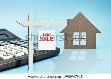 The concept of mortgage, sale and rental of housing and real estate. Mortgage credit lending. Calculator and a signboard for the sale or rent of a house. Copy space