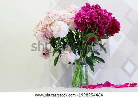 Bouquet of pink and white peonies on a wooden table, red garden peonies in a transparent glass vase jar on a white background, colorful assorted bouquet. Cozy home concept. vertical image. place for