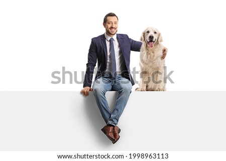 Man sitting on a blank panel and hugging a retriever dog isolated on white background