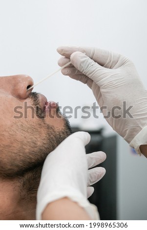 Coronavirus test - Close up of medical worker taking rapid nose swab for corona virus sample from potentially infected man