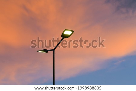 Public street lighting pole with LED lights with an amazing sunset color background. Royalty-Free Stock Photo #1998988805