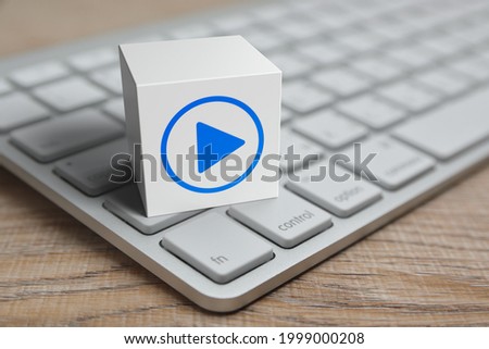 Play button on white block cube with modern computer keyboard on wooden table, Business music online concept