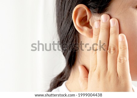 Young woman suffering from earache and tinnitus Causes of ear pain include otitis media and earwax buildup. Royalty-Free Stock Photo #1999004438
