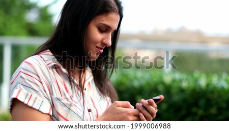 Millennial woman celebrating with fist success holding smartphone