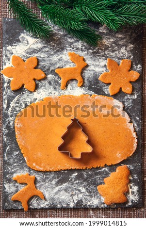 The process of making Christmas Ginger cookies. A Christmas tree-shaped mold on a raw dough for gingerbread cookies.