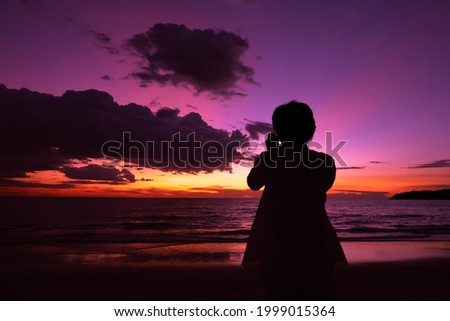 Silhouette of A man taking picture of beautiful sunset on the sea