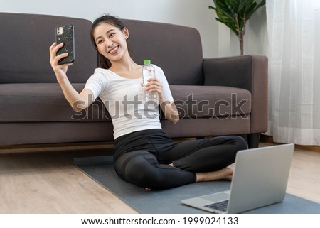Beautiful Asian woman is video conference with her friend after exercise at home already. Exercise and yoga for good health and good shape concept. 