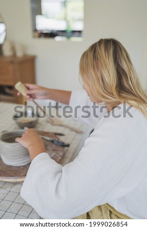 Female pottery artist making a vase in her home studio