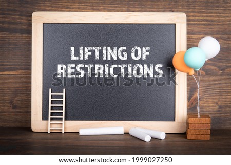 Lifting of restrictions. Chalk board on a wooden background.