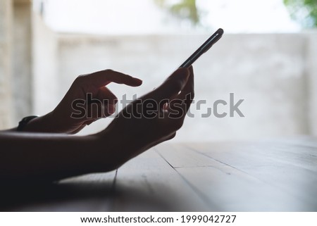 Closeup image of a hand holding and touching on mobile phone screen
