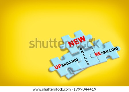 Reskilling, up skilling and new skills written on blue puzzle isolated on yellow background. Optimism and empathy personality concept with creativity idea Royalty-Free Stock Photo #1999044419