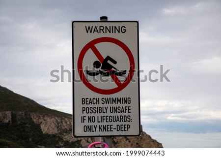 Close up on a sign saying it is unsafe to swim it  no lifeguard is on duty.