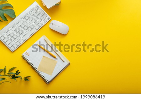 Office desk workspace on bright color yellow background. Office table Work space layout with computer keyboard, plant mouse notepad notes and copy space. Top view office table with palm plant.