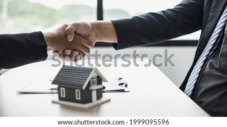Salesperson and customer shake hands after signing the contract, the salesperson explains the details and informs the customer of the reward. The concept of buying and selling houses.