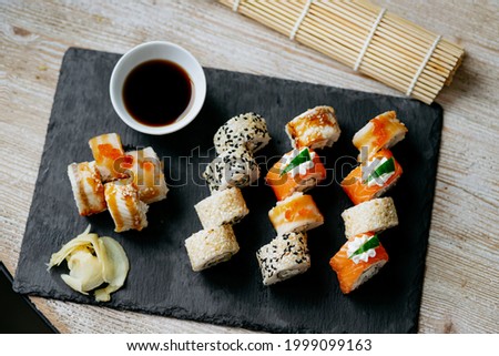 Assorted bright rolls with fish, cheese, eel, perch, caviar and soy iunagi sauce on a stone board