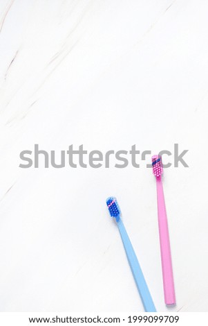 Teeth hygiene and oral dental care products on white marble table background with copy space. Pink and blue toothbrushes. Flat lay, top view composition, mockup