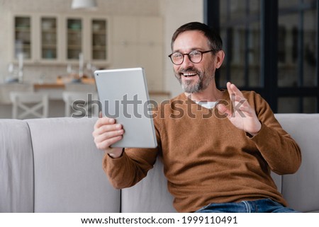 Mature middle-aged man father husband gesturing on camera talking communicating on video call conference with friends, children online using tablet, having conversation with colleagues Royalty-Free Stock Photo #1999110491