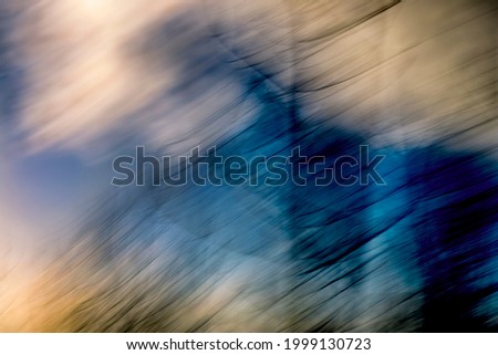 Hazy, fragmented, streaking trees under cloudy blue sky - abstract, motion-blurred background texture