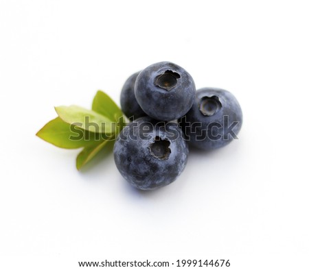 Blueberries on a white background. Berries and leaves isolated on white background. Four berries with green leaves.