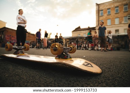  A skateboard with wheels on the asphalt against the background of a crowd of teenagers