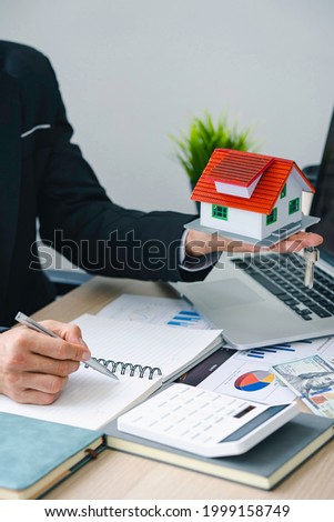 House model with the key and the real estate agent and customer discussing for the contract to buy house, insurance or loan real estate background.