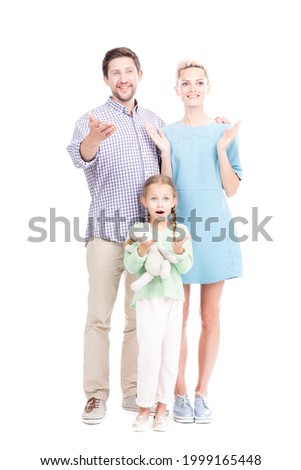 Vertical full length shot of modern man and woman standing with their little daughter surprised with something looking at camera, white background