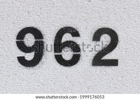 Black Number 962 on the white wall. Spray paint. Number nine hundred and sixty two.