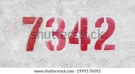 Red Number 7342 on the white wall. Spray paint. Number seven thousand three hundred forty two.