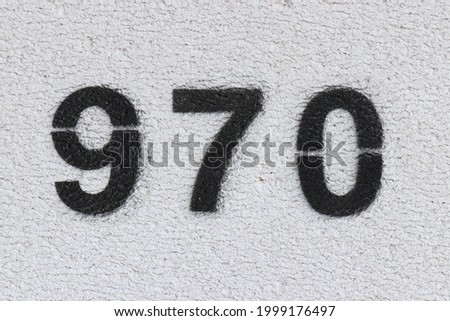 Black Number 970 on the white wall. Spray paint. Number nine hundred and seventy.