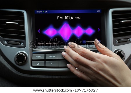 Woman tuning into a radio station in car Royalty-Free Stock Photo #1999176929