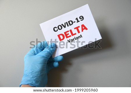 Doctor's hand in blue glove with white paper and text Covid-19 Delta Variant. Concept of medical variety delta variant and COVID-19. Concept words 'delta variant'. COVID-19 delta variant concept. Royalty-Free Stock Photo #1999205960