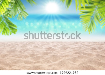 Beautiful sandy beach and sand dune with blurry tropical blue sea with palm leaves as frame , product display background concept