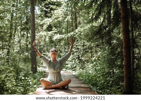 Woman doing breathing exercises in woods in fresh air. Concept of healthy lifestyle, solitude and merging with nature. High quality photo
