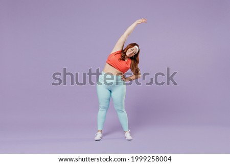 Full length young chubby overweight plus size big fat fit woman wear red top warm up training stand tilt body to sides with hand isolated on purple background gym. Workout sport motivation concept.