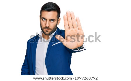 Young hispanic man wearing business jacket doing stop sing with palm of the hand. warning expression with negative and serious gesture on the face. 