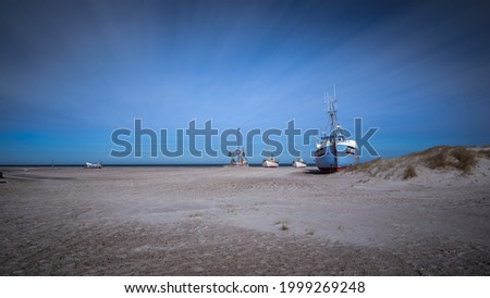 A creative fine art image, of fishing boats on the beach in Slettestrand, Denmark. 
Soft focus due to long exposure 