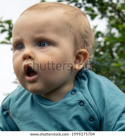 Adorable baby demonstrates real surprise emotions and observes something new for him with wide opened eyes and mouth. 