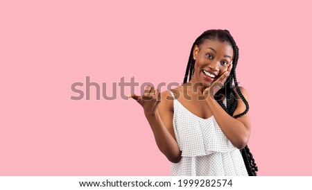 Summer sale. Emotional black lady pointing at blank space over pink studio background, banner design. Pretty African American woman in trendy clothes having special offer, advertising your product Royalty-Free Stock Photo #1999282574